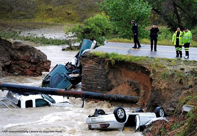 Several trucks partially submerged in a creek below a washed out road after the 2013 South Platte flood.