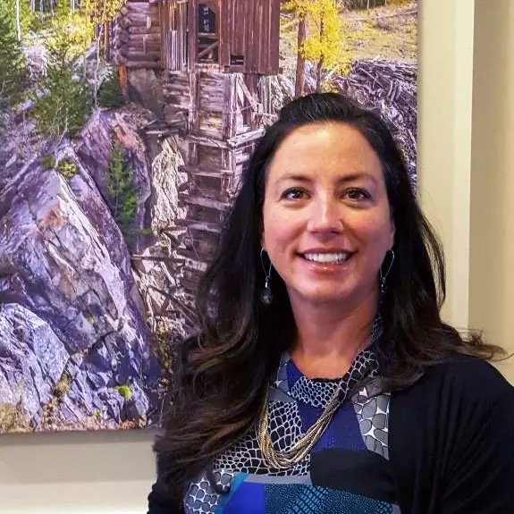 Becky smiling in front of a painting of an old mine structure.