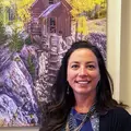 Becky smiling in front of a painting of an old mine structure.