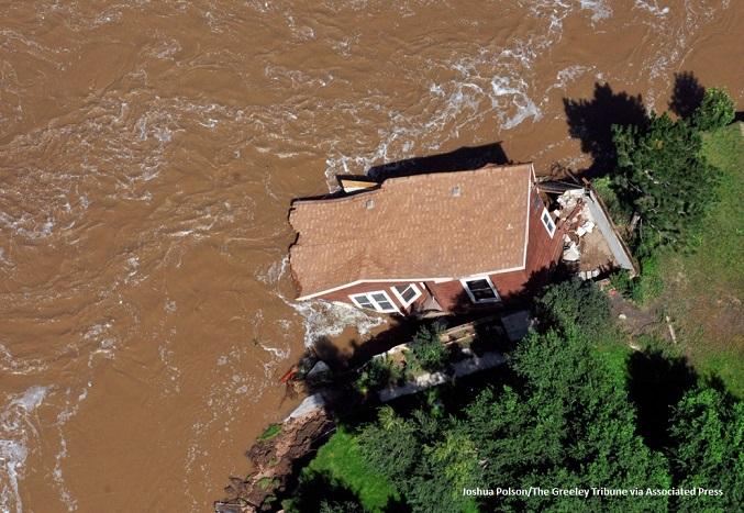 Overhead view of a house partially washed into a flooded river during the 2013 South Platte flood