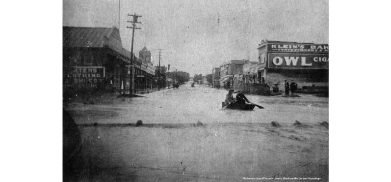 Two men paddle a canoe down the flooded main street of Walsenburg in 1907