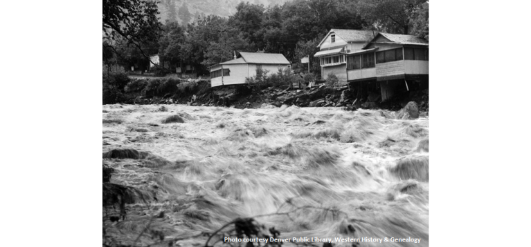 Two houses sit precariously at the edge of a river rushing with flood waters in Eldorado Springs 1938