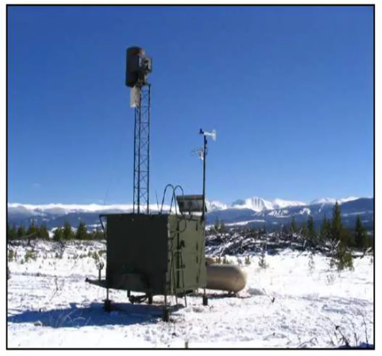 A square ground based cloud seeding generator sits in a snow-covered field